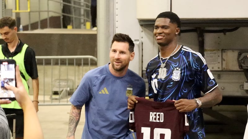 Texas A&M quarterback Marcel Reed (right) gives Argentina forward Lionel Messi an Aggie jersey...
